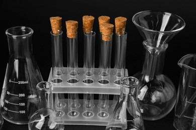 Photo of Different laboratory flasks and test tubes on black background