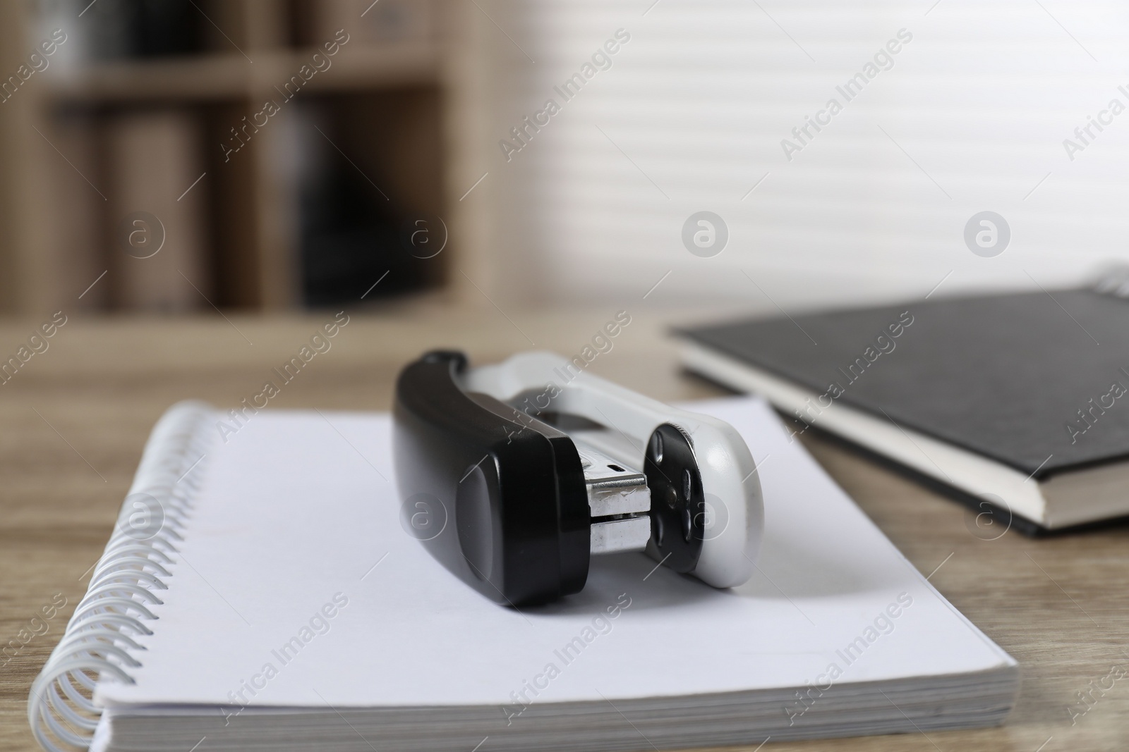 Photo of Stapler and notebook on wooden table indoors, closeup