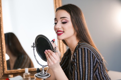 Portrait of beautiful woman applying makeup indoors