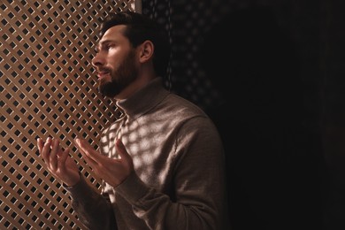 Man talking to priest during confession in booth, space for text