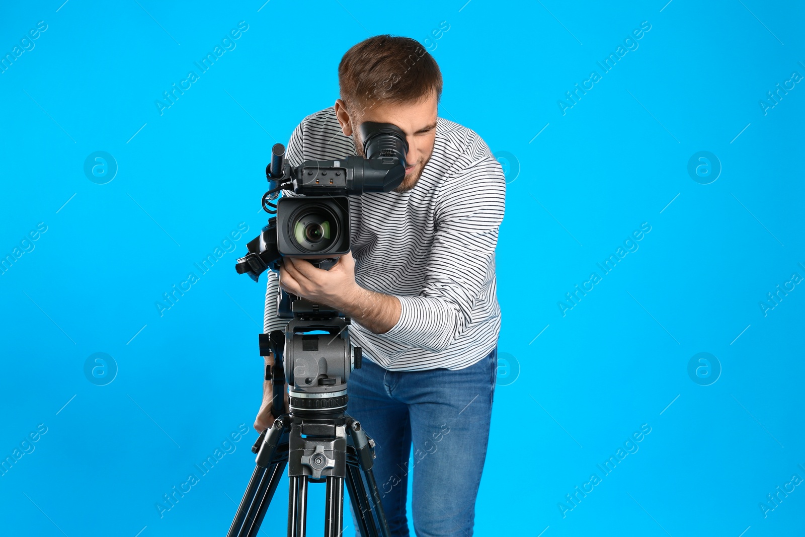 Photo of Operator with professional video camera on blue background