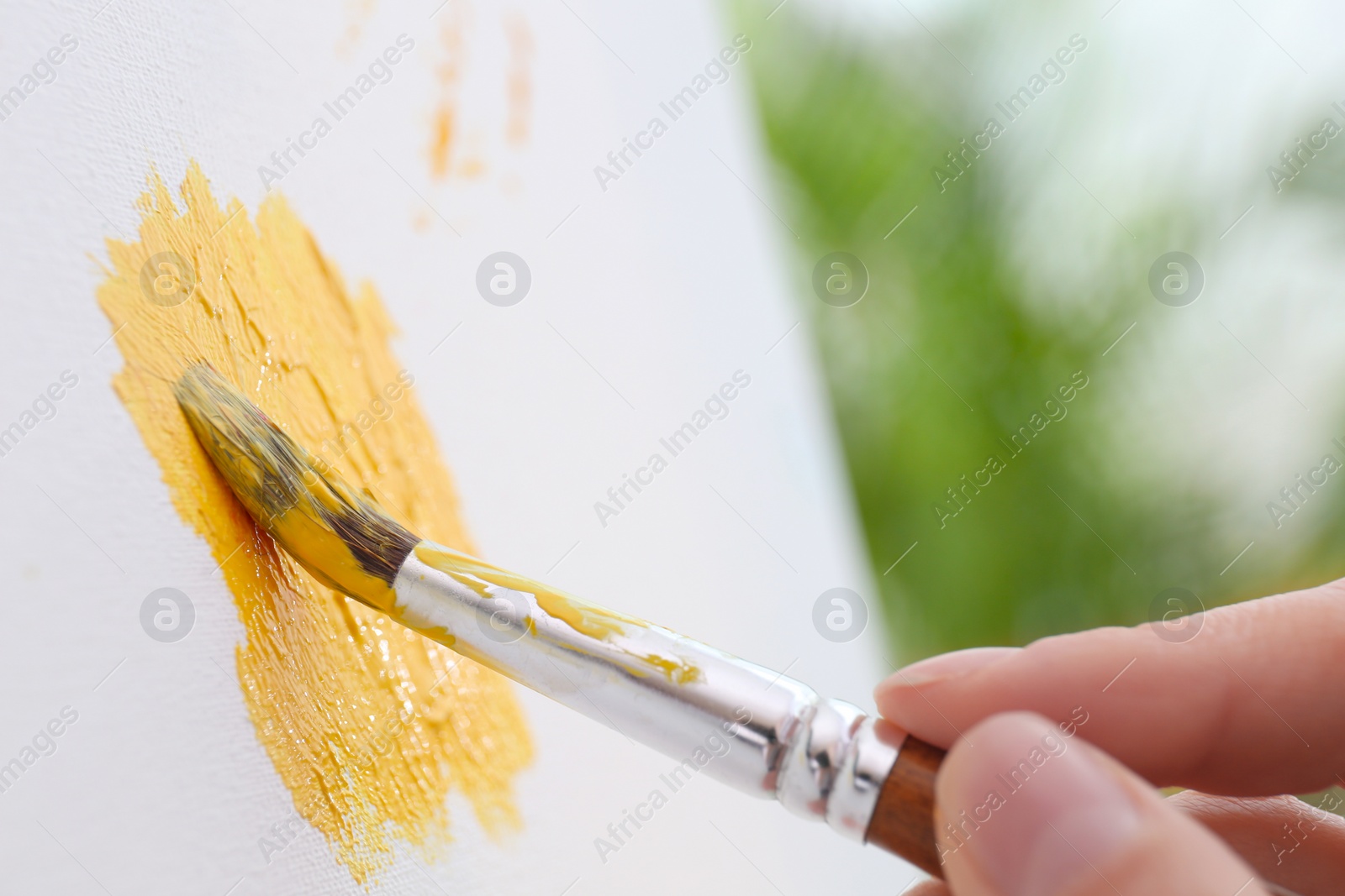 Photo of Artist painting on canvas with brush, closeup