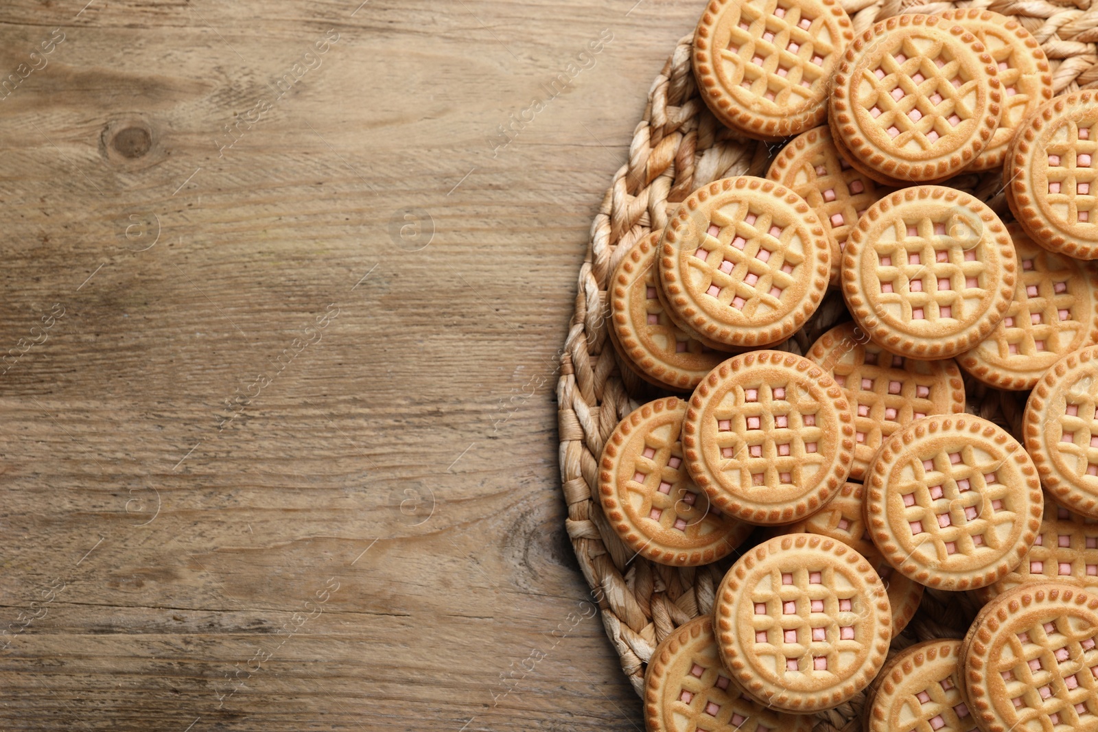 Photo of Tasty sandwich cookies with cream on wooden table, top view. Space for text