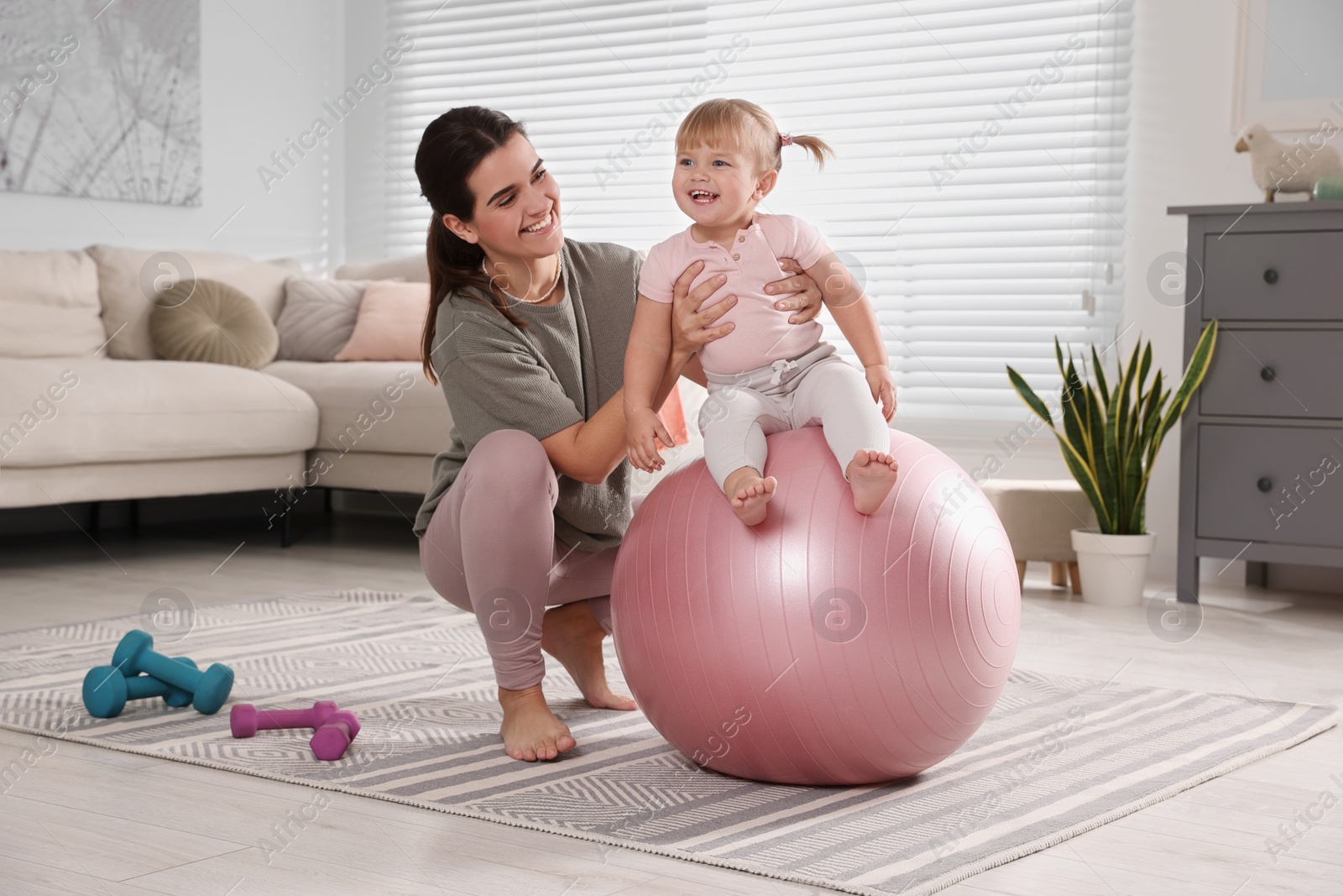 Photo of Mother doing exercise with her daughter on fitball at home