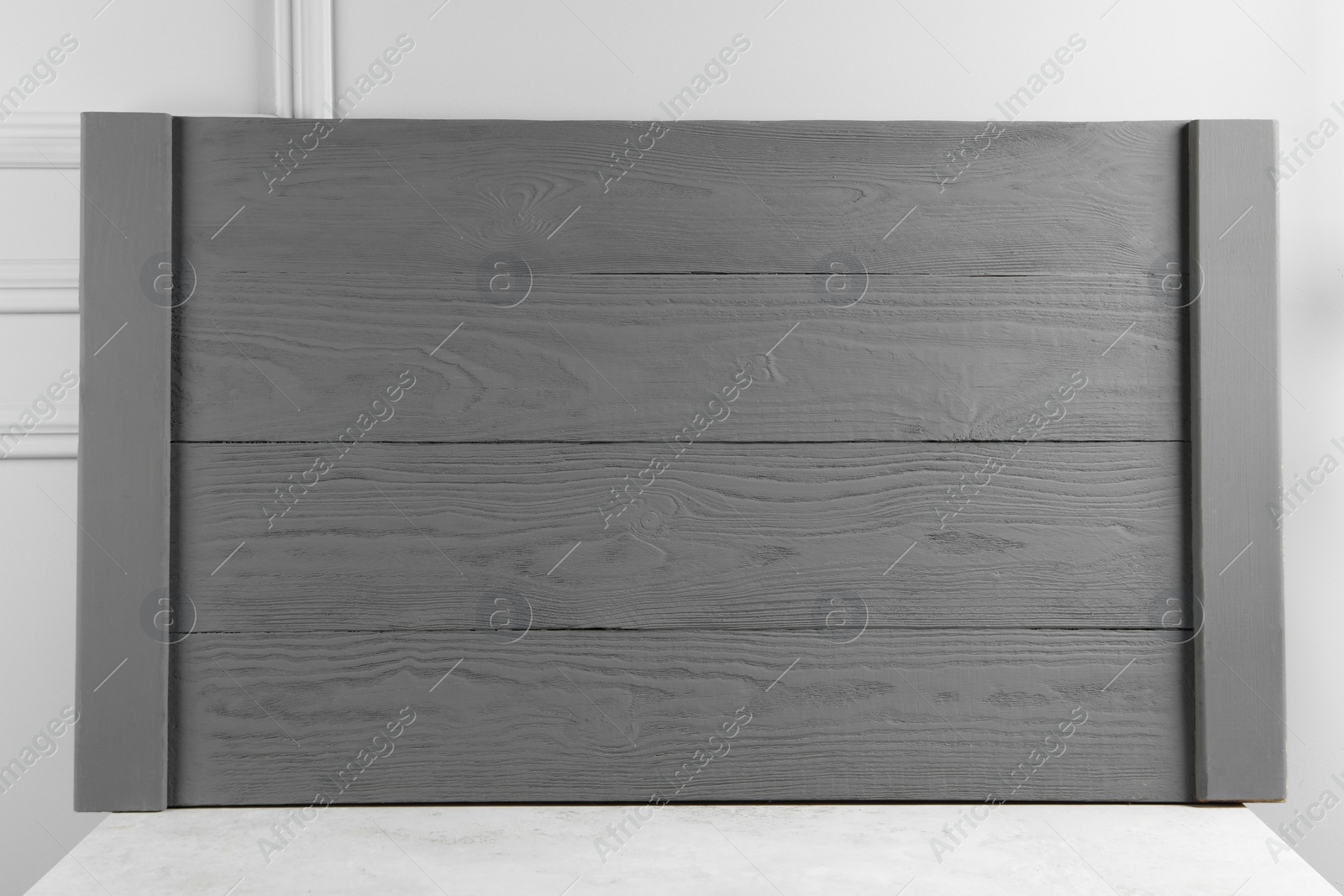 Photo of Wooden board on table near light grey wall