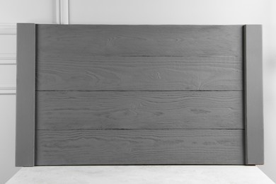 Wooden board on table near light grey wall