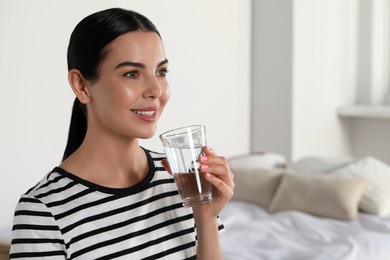 Photo of Young woman with glass of water indoors, space for text. Refreshing drink