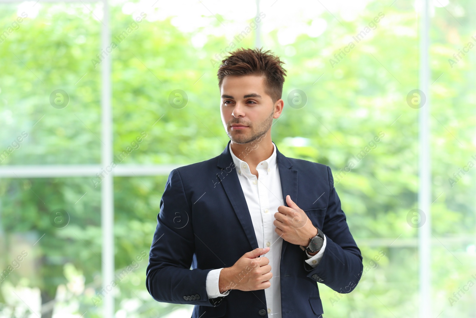 Photo of Portrait of handsome young man in elegant suit against window
