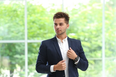 Portrait of handsome young man in elegant suit against window