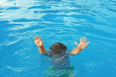 Little child sinking in outdoor swimming pool. Dangerous situation