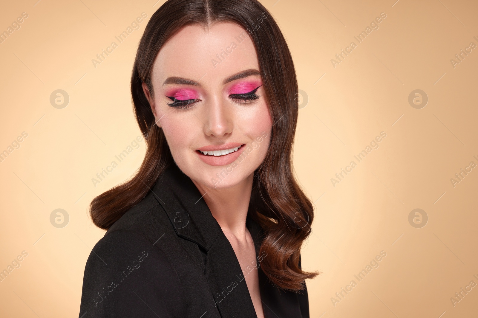 Photo of Portrait of beautiful young woman with makeup and gorgeous hair styling on beige background. Space for text