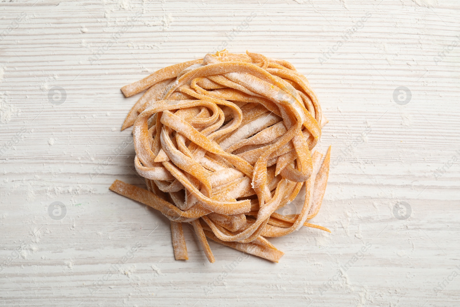 Photo of Pasta painted with food coloring and flour on white wooden table, top view