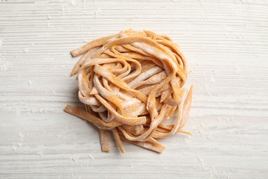 Photo of Pasta painted with food coloring and flour on white wooden table, top view