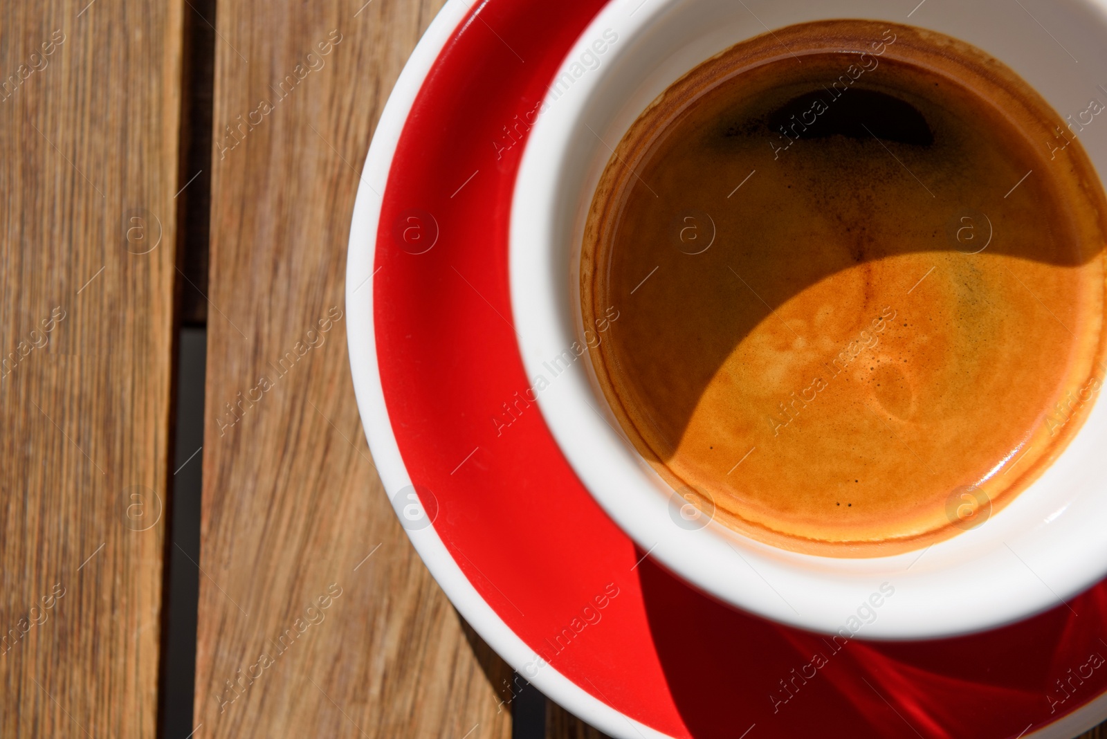 Photo of Cup of aromatic hot coffee on wooden table, top view. Space for text