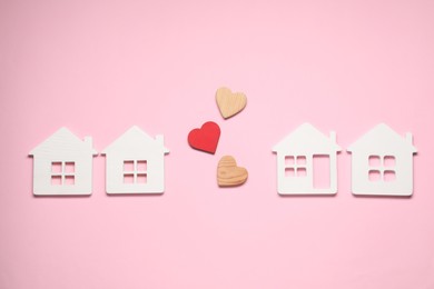 Photo of Long-distance relationship concept. Decorative hearts between white house models on pink background, flat lay