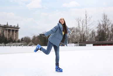 Happy woman skating along ice rink outdoors