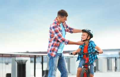 Dad teaching son to ride bicycle outdoors