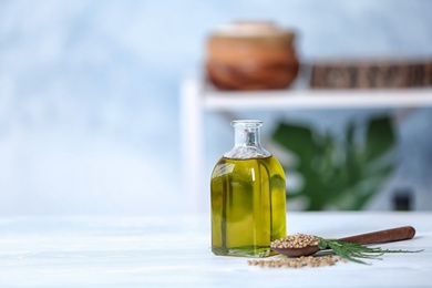 Photo of Bottle with hemp oil, seeds and fresh leaves on light table. Space for text