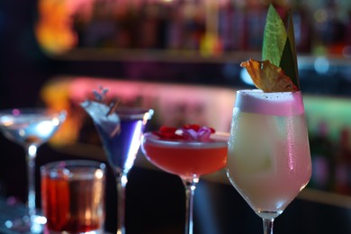 Photo of Different fresh alcoholic cocktails on blurred background, closeup. Space for text