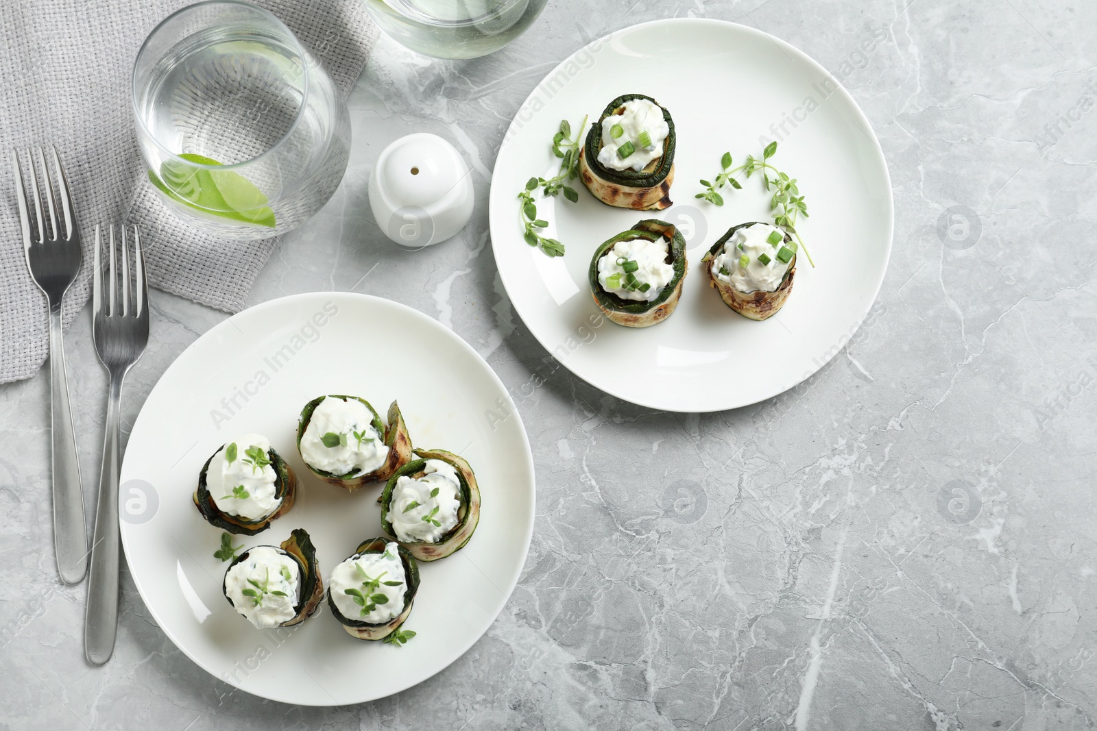 Photo of Stuffed zucchini rolls served on grey marble table, flat lay. Space for text