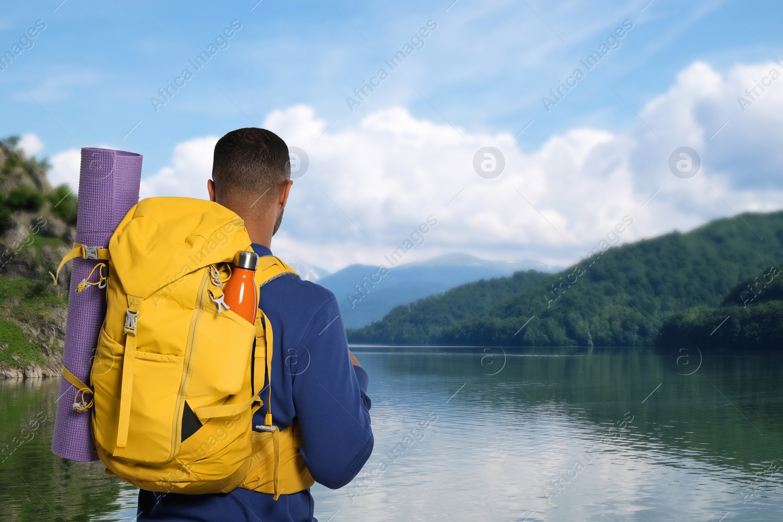 Image of Tourist with backpack near lake, back view