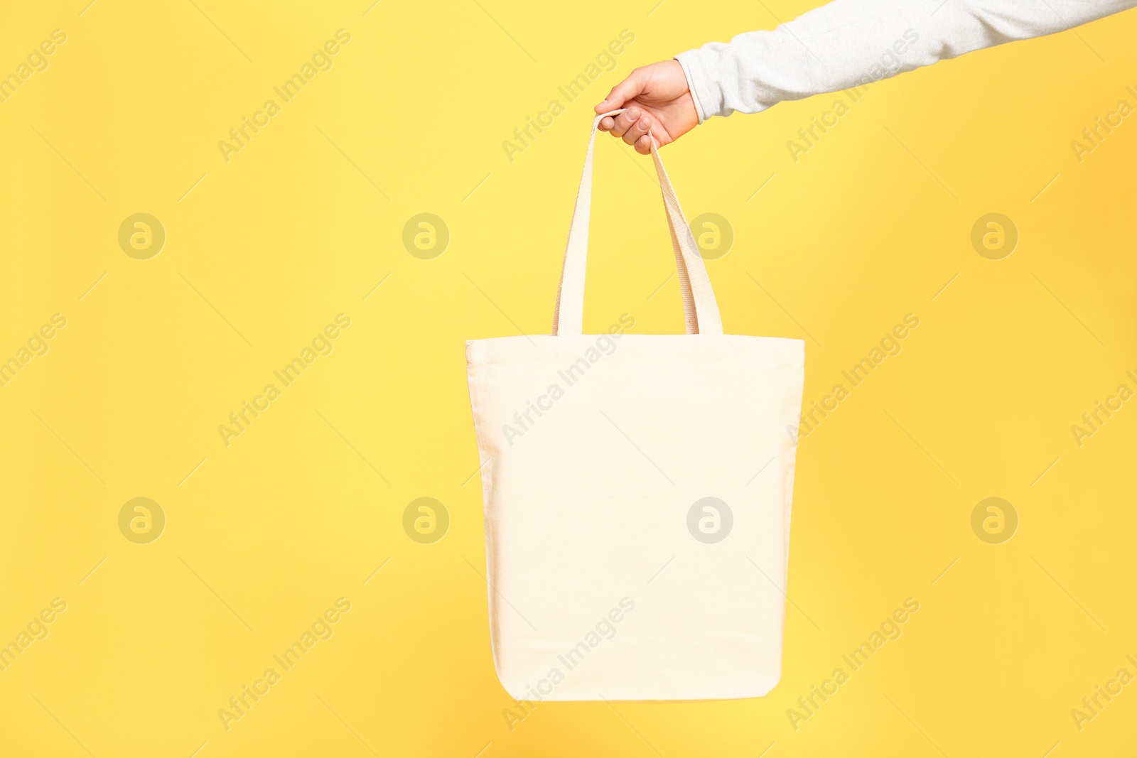 Photo of Young man with eco bag on yellow background, closeup