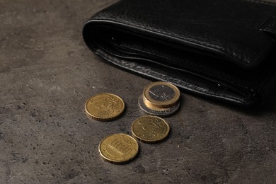 Photo of Poverty. Black wallet and coins on grey table, closeup