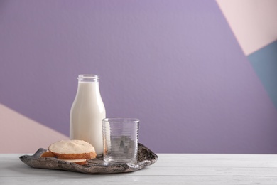 Photo of Bottle of milk and sliced bread with butter on table against color background