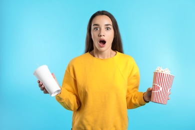 Photo of Emotional woman with popcorn and beverage during cinema show on color background