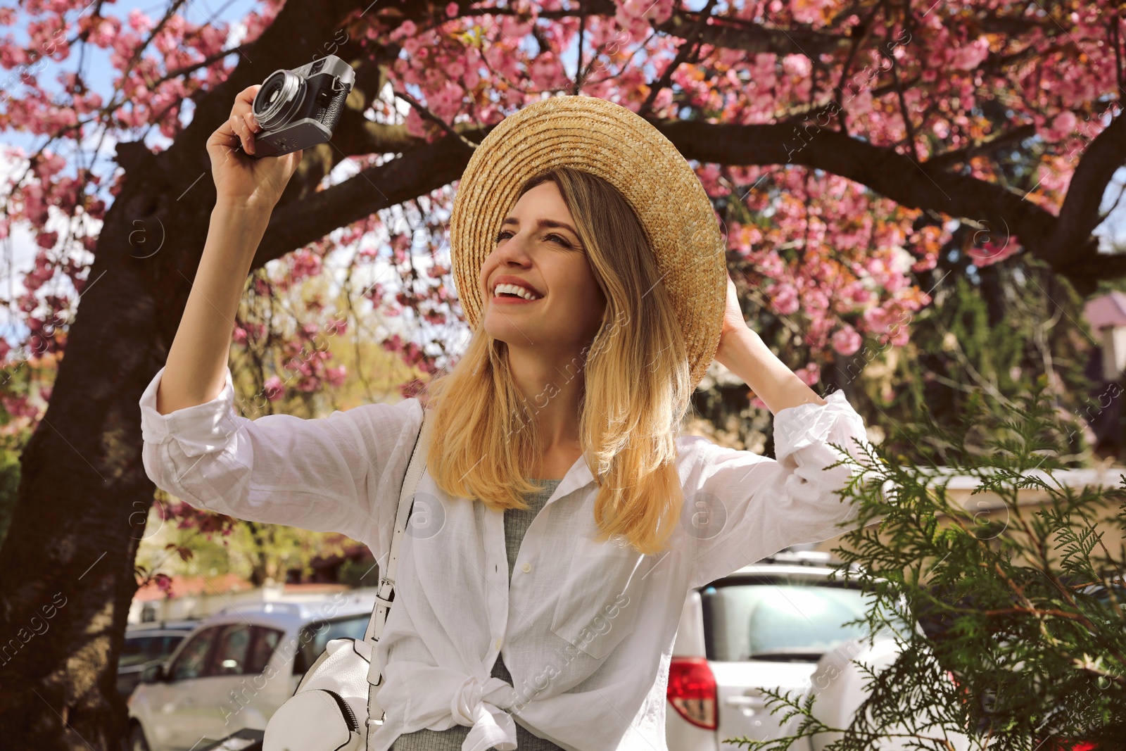 Photo of Happy female tourist with camera outdoors on spring day