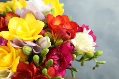 Photo of Beautiful bright spring freesia flowers on color background, closeup