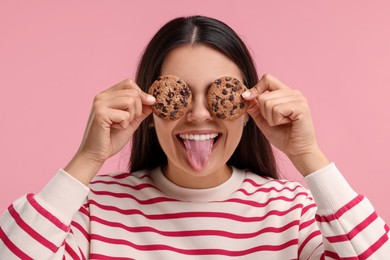 Photo of Young woman with chocolate chip cookies on pink background