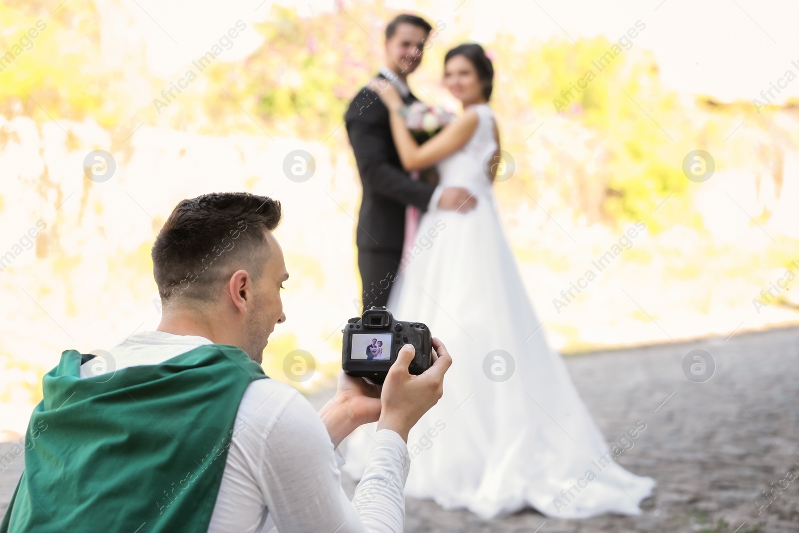 Photo of Professional photographer taking photo of wedding couple, outdoors