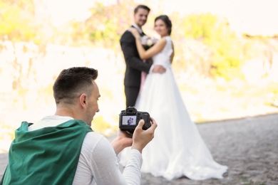 Professional photographer taking photo of wedding couple, outdoors