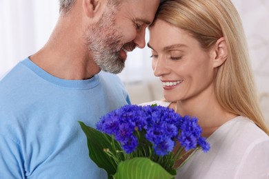 Happy affectionate couple with bouquet of cornflowers at home. Romantic date