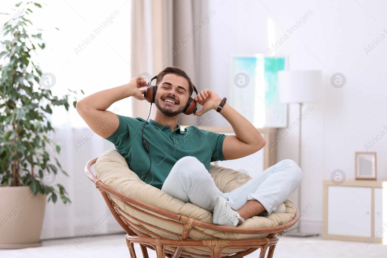 Photo of Handsome young man listening music in armchair at home