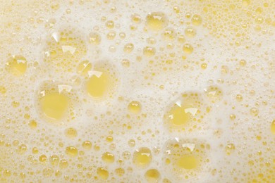 Photo of White washing foam on yellow background, top view