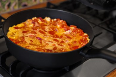 Photo of Tasty fried eggs with tomatoes in frying pan on stove, closeup