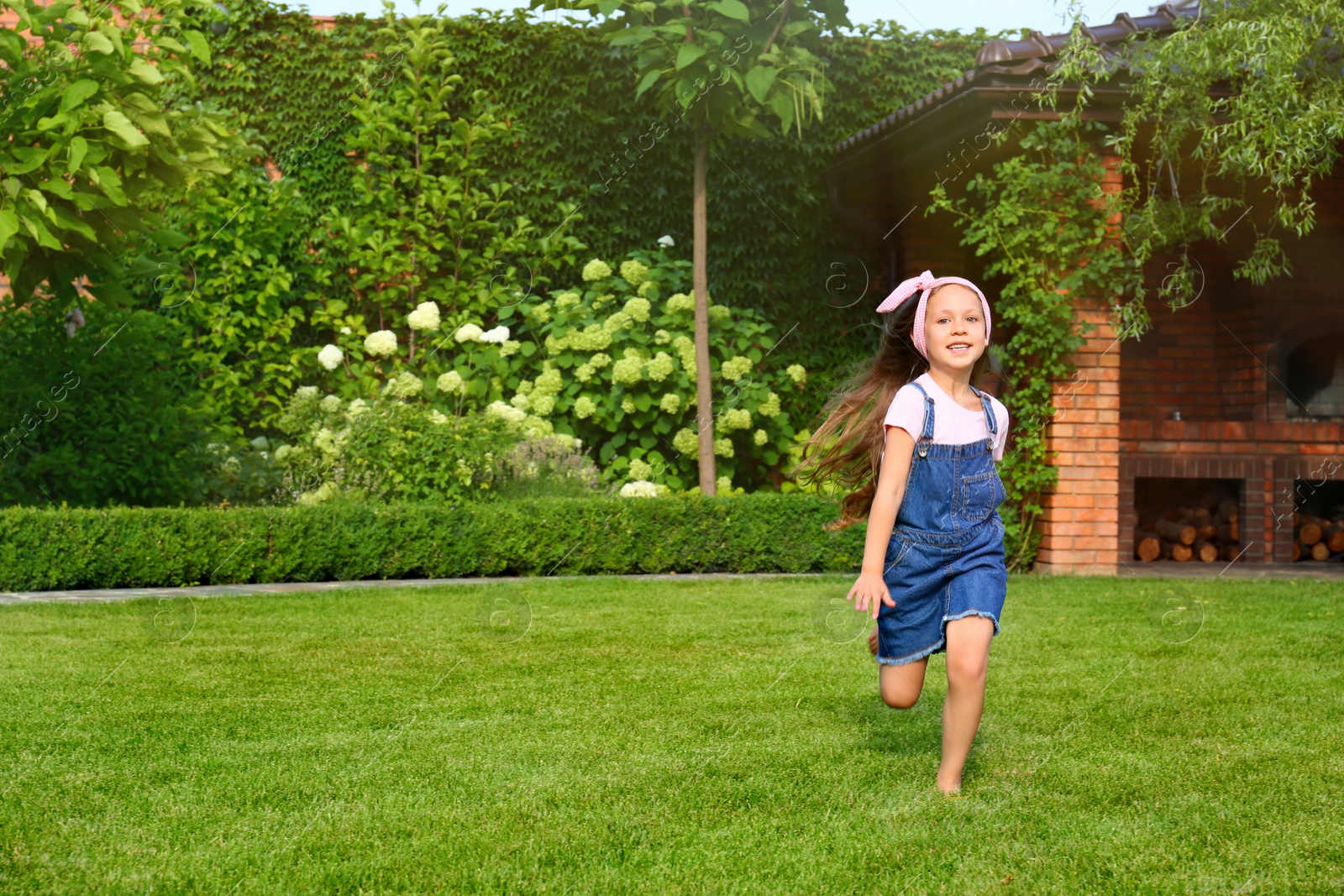 Photo of Cute little girl running in green park on summer day