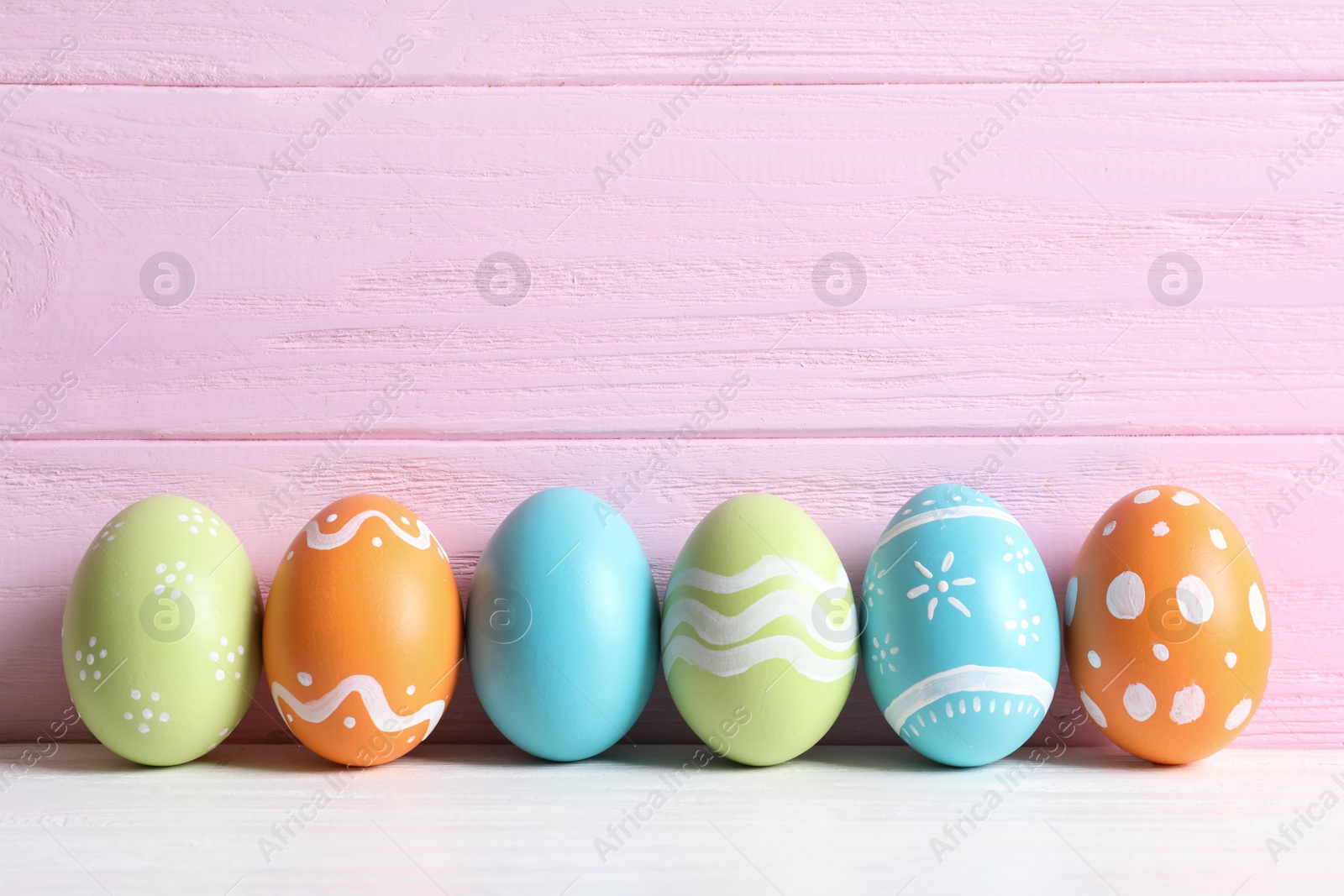 Photo of Colorful painted Easter eggs on table against wooden background, space for text