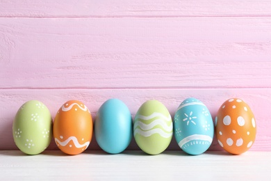 Photo of Colorful painted Easter eggs on table against wooden background, space for text