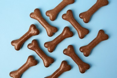 Photo of Bone shaped dog cookies on light blue background, flat lay