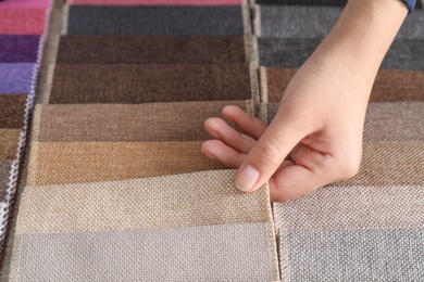 Young woman choosing among upholstery fabric samples, closeup. Interior design