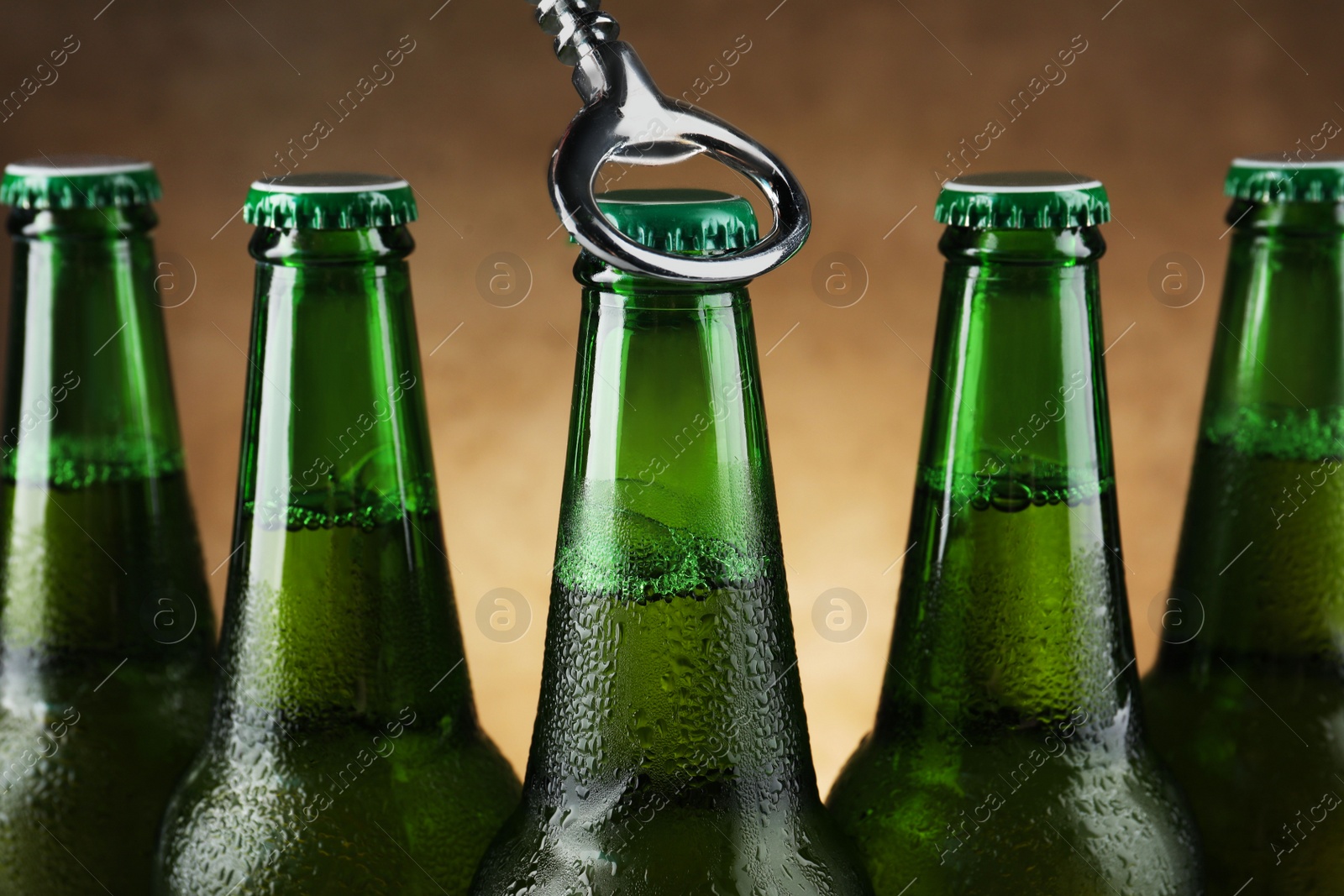 Photo of Opening bottle of beer on brown background, closeup