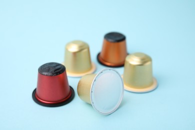 Many coffee capsules on light blue background, closeup