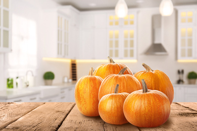 Image of Fresh pumpkins on wooden table in kitchen. Space for text