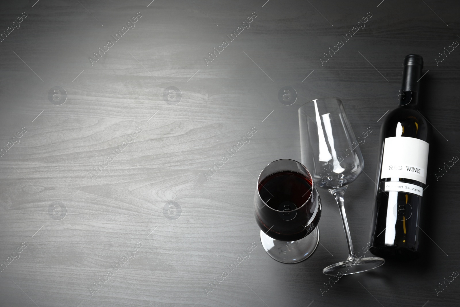 Photo of Glasses and bottle with red wine on dark background, view from above. Space for text