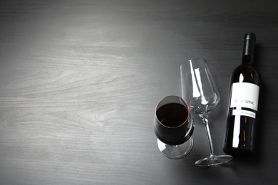 Glasses and bottle with red wine on dark background, view from above. Space for text