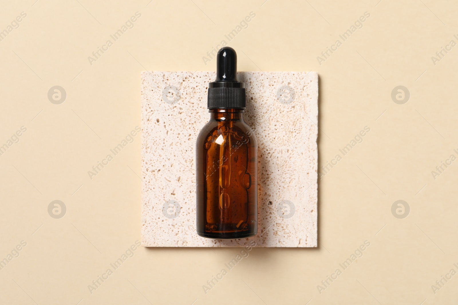 Photo of Bottle of cosmetic serum on beige background, top view