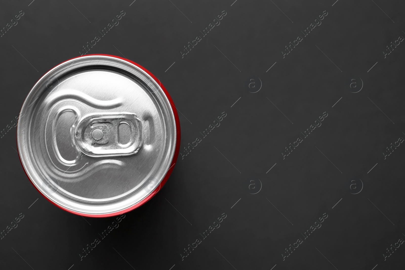 Photo of Energy drink in can on black background, top view. Space for text